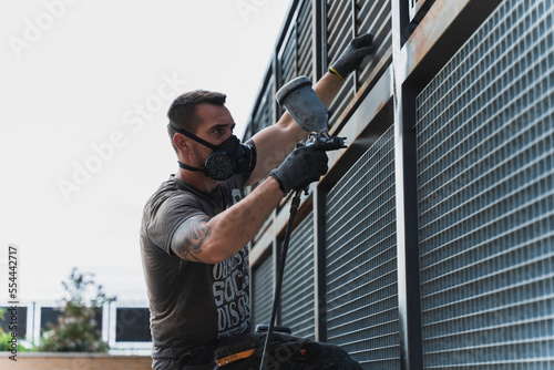Painter with a spray gun painting bars