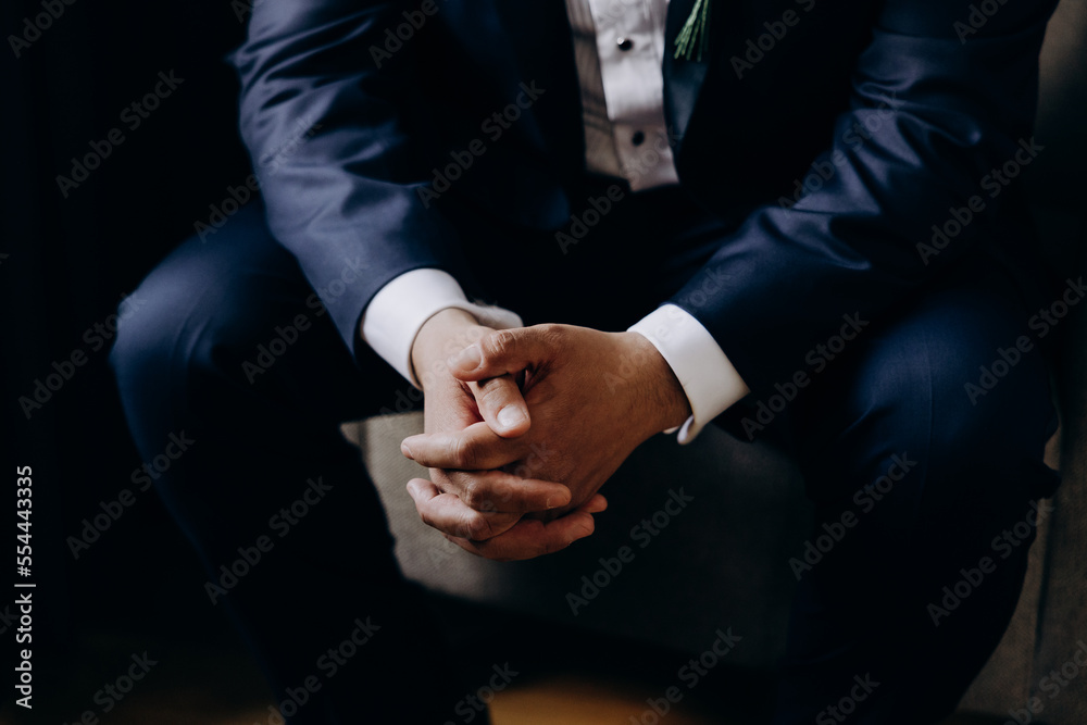 Wedding. A man in a suit and white shirt sits on a chair with his arms folded Wedding. A man in a suit and white shirt sits on a chair with his arms folded