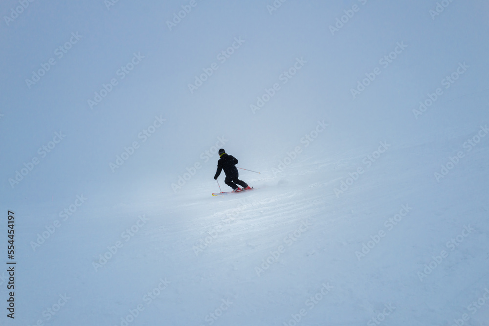 a skier during a snowfall descends at great speed down the mountain