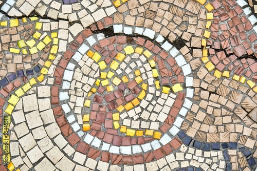 Old cracked mosaic attracts scientists and tourist attention with durability over years. Racks on stone mosaic wall have historical significance closeup