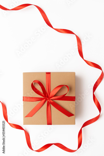 Flat lay of craft present box with red bow and ribbon on the white background