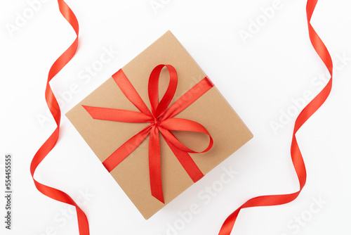 Flat lay of craft present box with red bow and ribbons on the white background