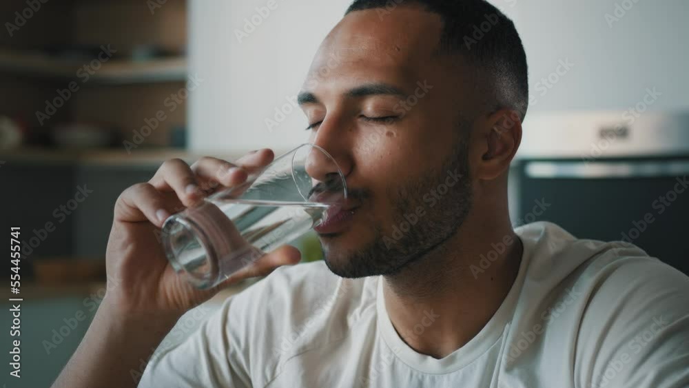 African American healthy sportsman ethnic male guy man athlete sporty trainer indoors drink still cold water with glass drinking refreshment fresh nutrition aqua balance body health care weight loss