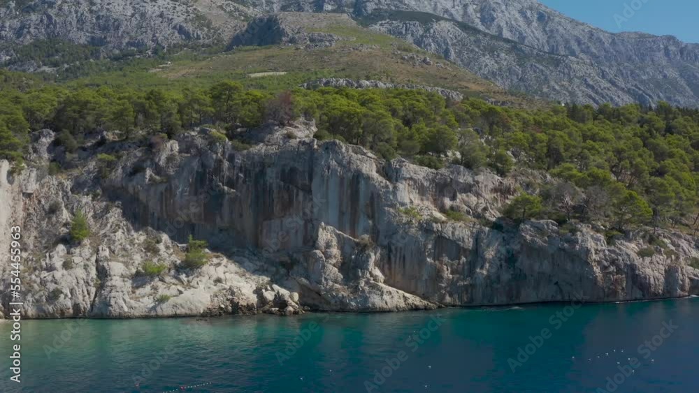 Blue Adriatic Sea. High mountains. Rocky beautiful coast. Blue sky. The man floats on the board. Summer, sunny landscape. Beauty of nature. Green Forest. Croatia. Drone video Blue Adriatic Sea. High mountains. Rocky beautiful coast. Blue sky. The man floats on the board. Summer, sunny landscape. Beauty of nature. Green Forest. Croatia. Drone video