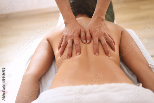 Hands pressing back of woman in massage center in close up shot and from above