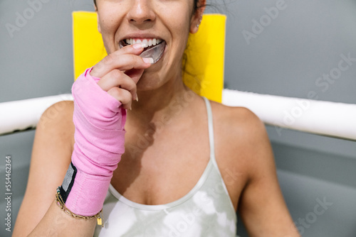 A young girl putting on a mouth guard before boxing training photo