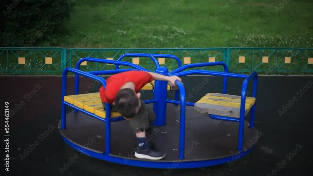 A child on a merry-go-round. A boy on the playground. A child alone in the summer. Child, carousel, playground, playground, spinning, play, details, summer, recreation, entertainment, boredom, red, bl