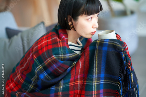 ブランケットをかけてマグを持つ若い女性 photo