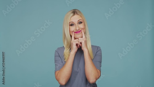 Young beautiful blond girl in the studio. Portrait of emotional girl on blue background.