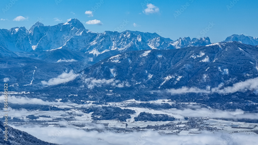 Obraz premium Panoramic view of snowcapped mountain summit Mangart and Jalovec in Julian Alps seen from Kobesnock near Bad Bleiberg, Carinthia (Kaernten), Austria, Europe. Snow covered winter wonderland foreground