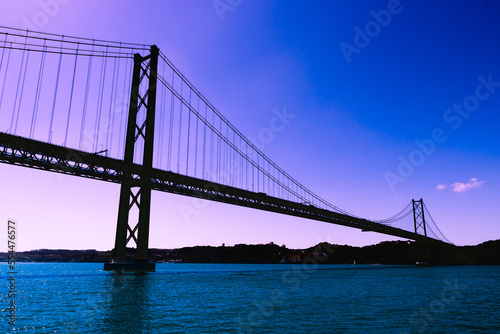 Silhouette of large metal bridge across the sea Strait on the background of a fantastic purple sky © Bogdan
