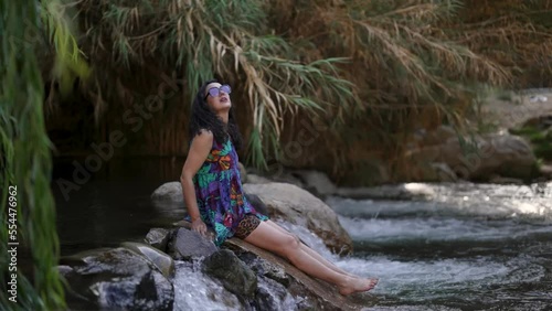 latin mid adult woman on a stone in the Elqui river enjoying the climate and nature of the Valle del Elqui, Cochiguaz photo