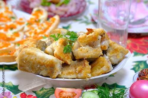 Ukrainian Easter festive dishes. Festive table setting. Bright colored eggs, cake Paska, traditional salad olivier, fried fish, sandwiches with red caviar, vegetables, green, homemade sausage, herring