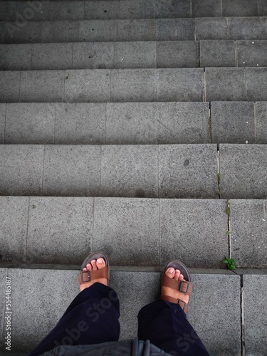 Men legs in sandals descending the stairs in the city
