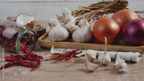 Slide shot slow motion garlic and chilli drop onto chopping board.