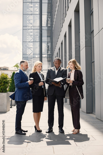 Business people standing and talk to each other in front of modern office