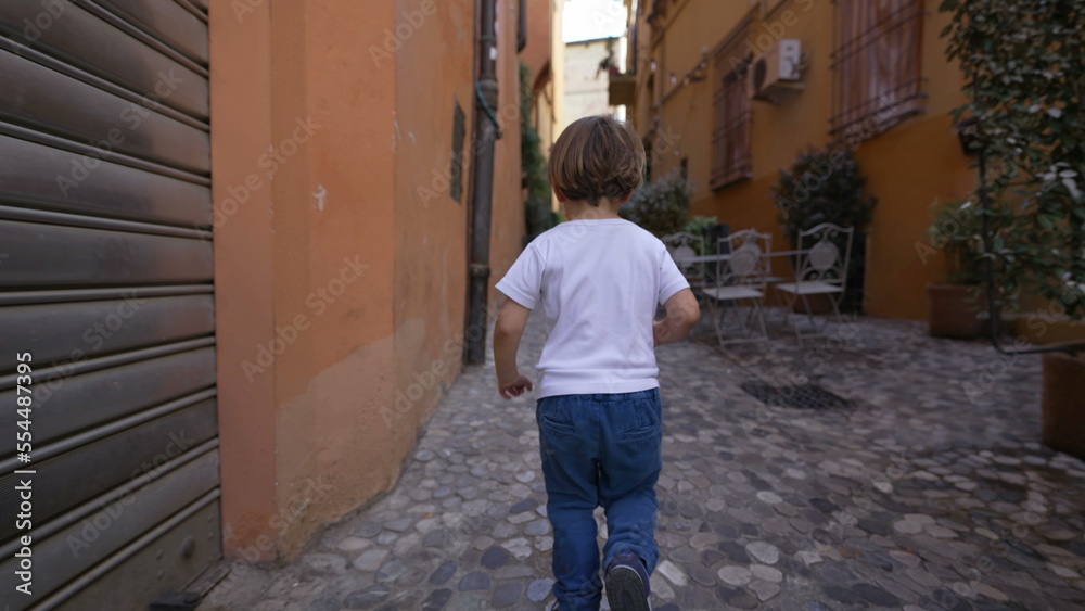 Back of child running in old european street. One little boy runs in Italian alley