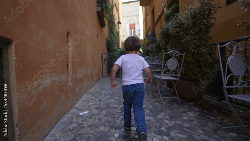 Back of child running in old european street. One little boy runs in Italian alley © Marco
