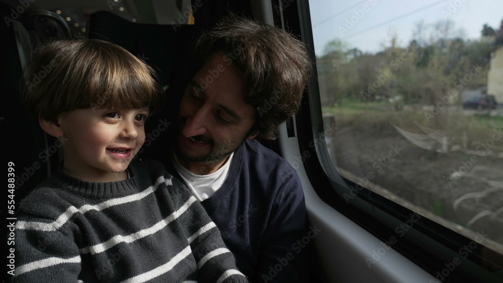 Parent and child traveling by train together. Father and son staring at window inside high speed transportation