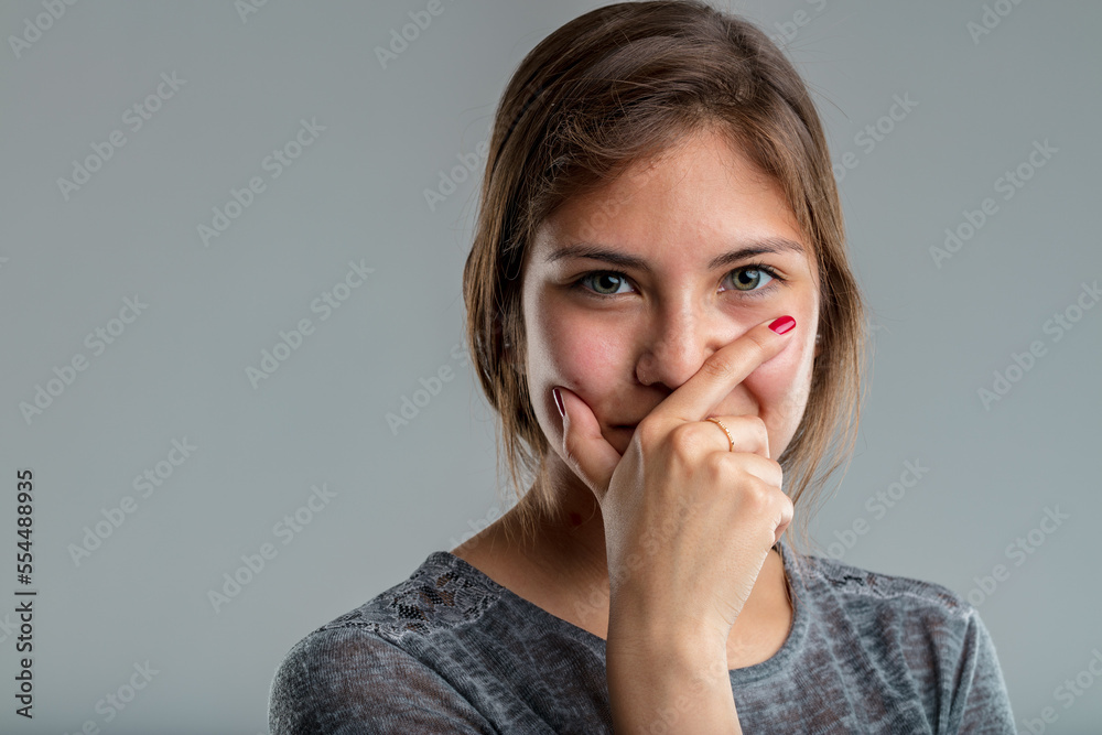 closeup pretty young woman hides her mouth behind a hand closeup pretty young woman hides her mouth behind a hand