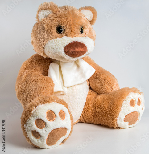 Teddy bear with a bow on a white background. Soft children's toy.