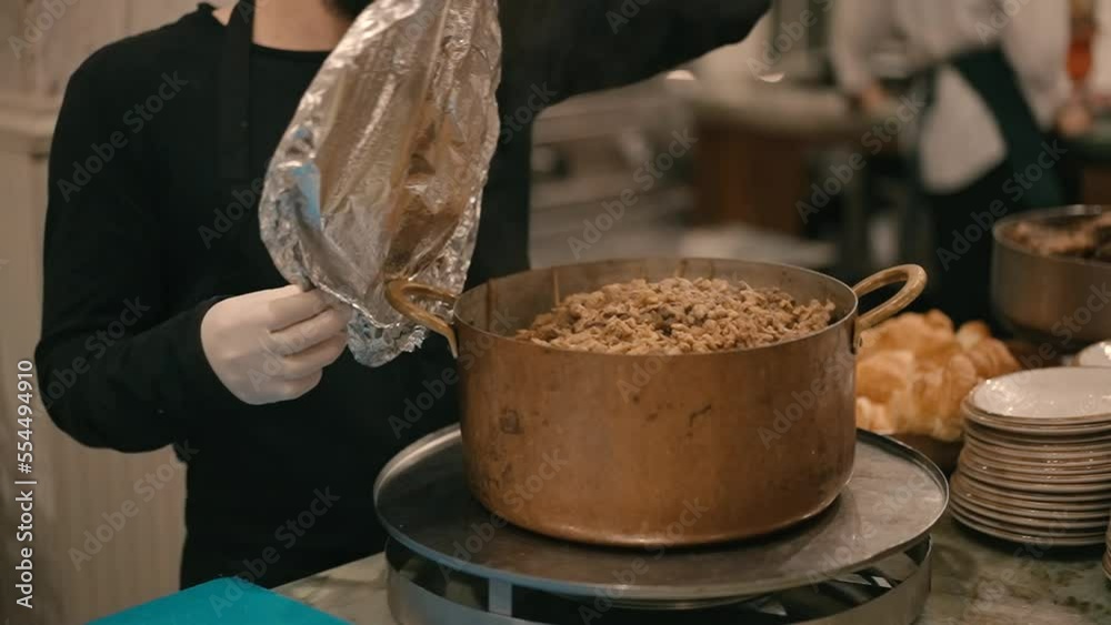 Getting Cooked A kitchen worker opens a pot with cooked meat inside. Steam comes out ...