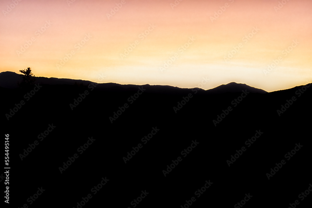 Obraz premium Yellow orange pastel sunset vibrant color in Aspen, Colorado with rocky mountains peak at twilight with mountain ridge dark silhouette