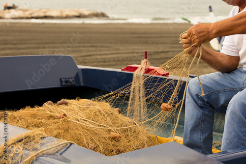 fishing net in the hands of a fisherman, preparing gear to go out to sea, in the background the Mediterranean coast