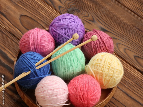 Colorful knitting yarn and knitting needles on wooden background as hobby collection