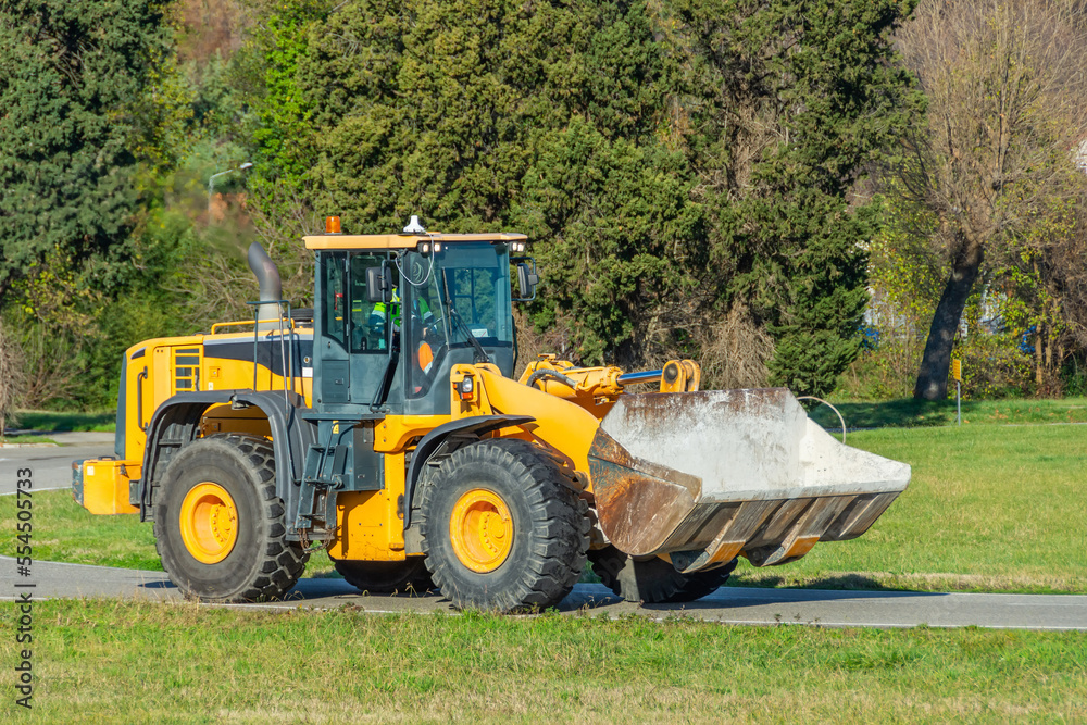 Grader and Excavator Construction Equipment on the background of trees rides on the road. Grader and Excavator Construction Equipment on the background of trees rides on the road.