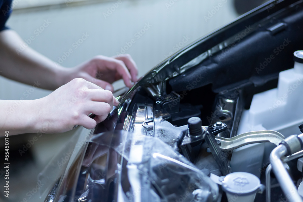 Installation of a protective film on the headlights of the car.Car body protection.