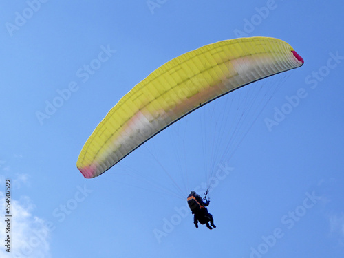 Yellow tandem Paraglider flying in a blue sky 