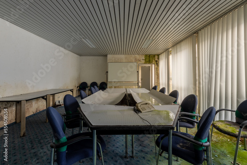 A abandoned and moldy meeting room, moss growing on the floor