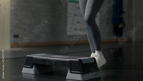 A woman doing exercises on a step platform in slow motion. Active training of female legs in the gym. close up