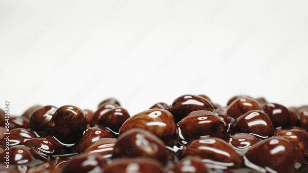 Close-up hazelnuts pile covered with honey or caramel sauce, lot of caramelized whole nuts on white background dolly slide shot. Place for title, text or logo, template for adding text Close-up hazelnuts pile covered with honey or caramel sauce, lot of caramelized whole nuts on white background dolly slide shot. Place for title, text or logo, template for adding text