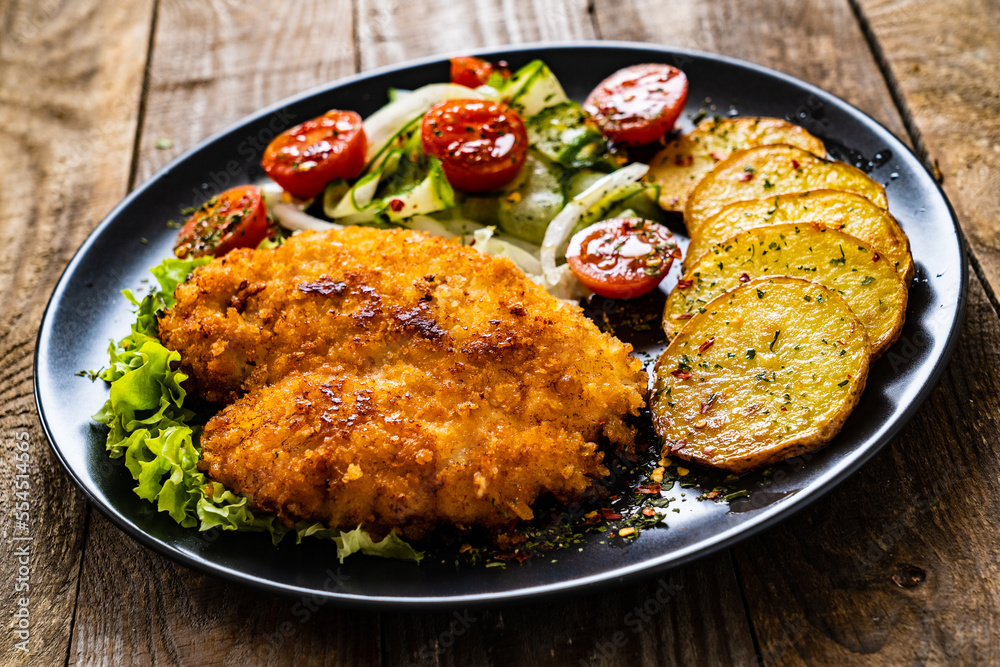 Breaded fried pork chop with fried potatoes and greens on wooden table
Breaded fried pork chop with fried potatoes and greens on wooden table