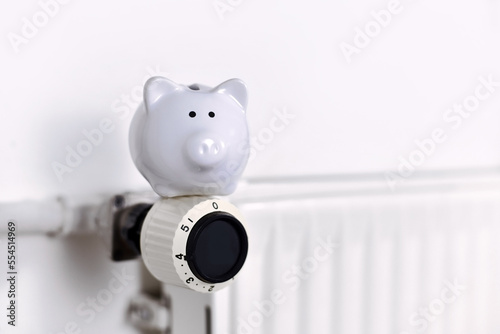 Saving money for gas for heating concept with piggy bank on radiator with copy space