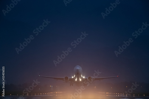 passenger plane takes off at night, airfield lights photo