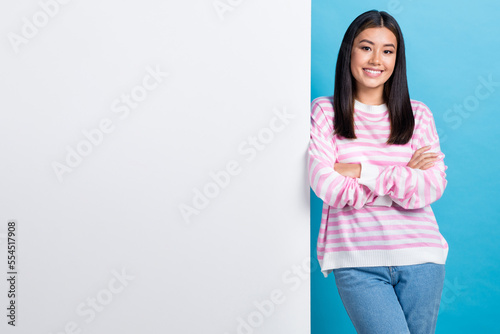 Photo of nice charming smile satisfied korean business lady folded arms stay near big empty space placard isolated on blue color background