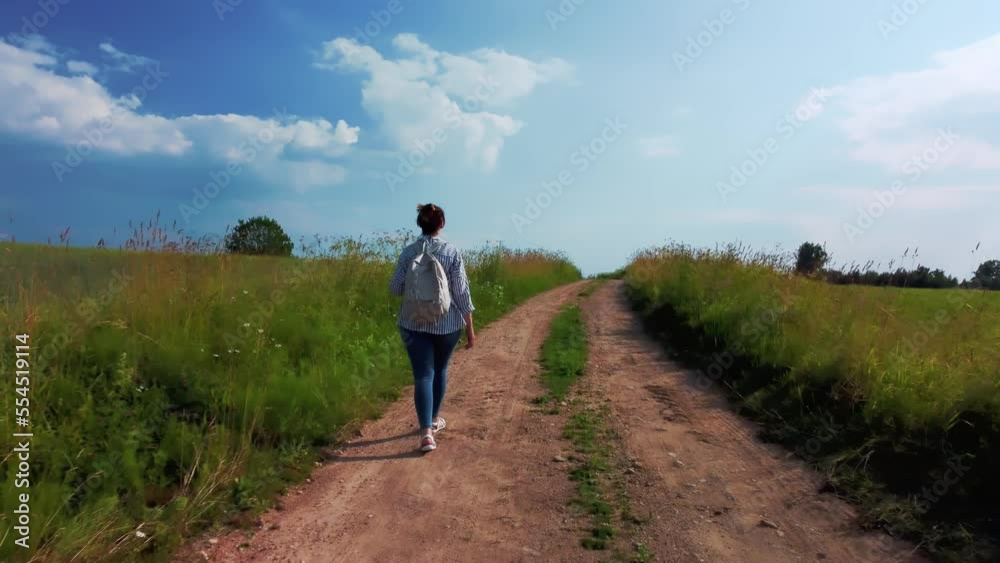 Portrait of a female tourist walking along the road in a green field in summer. Portrait of a female tourist walking along the road in a green field in summer.