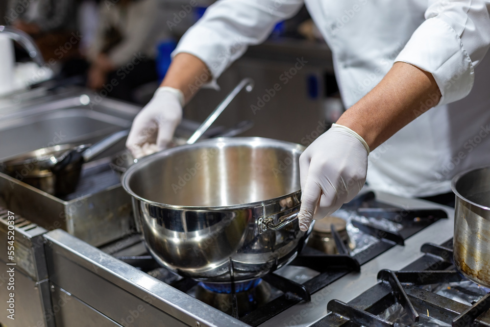 A cook stirring pots in the kitchen. Big pots in the kitchen A cook stirring pots in the kitchen. Big pots in the kitchen
