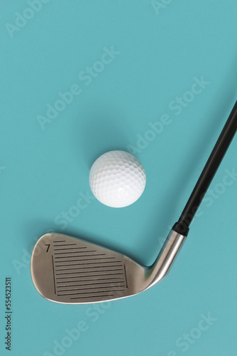 Closeup of golf club and golf ball isolated on light turquoise blue background. Space for text.