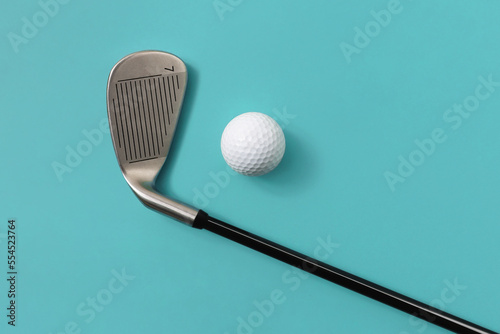 Golf club and golf ball isolated on light turquoise blue background. Concept of sport. Space for text.