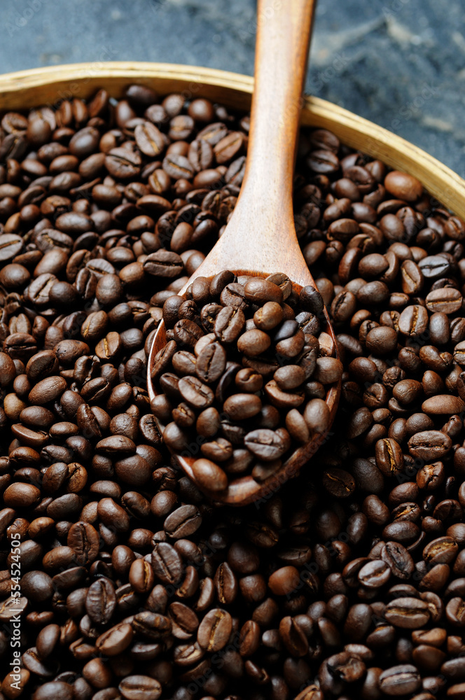Fototapeta premium Dark roasted coffee beans with wooden scoop