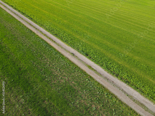 View from above of a gravel road between fields of grass in the countryside