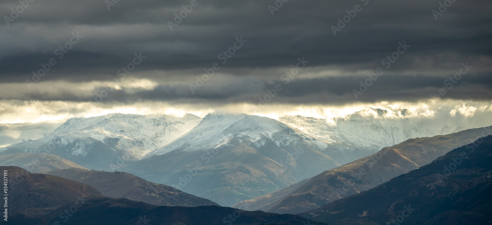 Stormy clouds with sunbeams over snowy mountains in Granada (Spain)