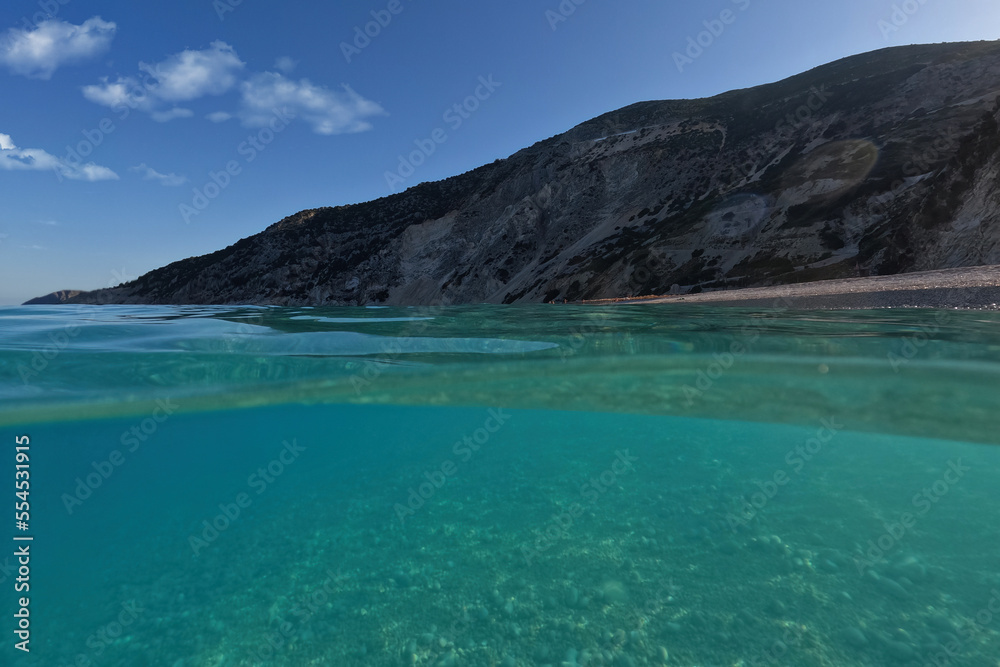 Underwater split sea level photo of famous paradise pebble beach of Myrtos one of the best in island of Kefalonia, Ionian, Greece