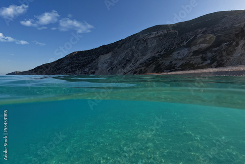 Underwater split sea level photo of famous paradise pebble beach of Myrtos one of the best in island of Kefalonia, Ionian, Greece