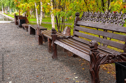 City brown wooden bench on the street in the autumn park
