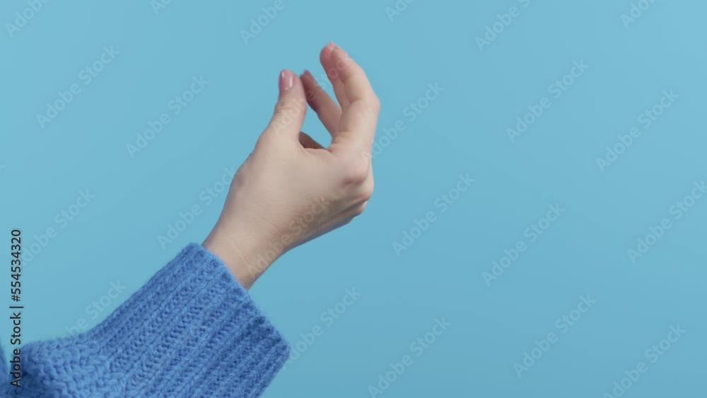 Unrecognizable woman snaps fingers on blue studio background. Snapping to make sound, bring